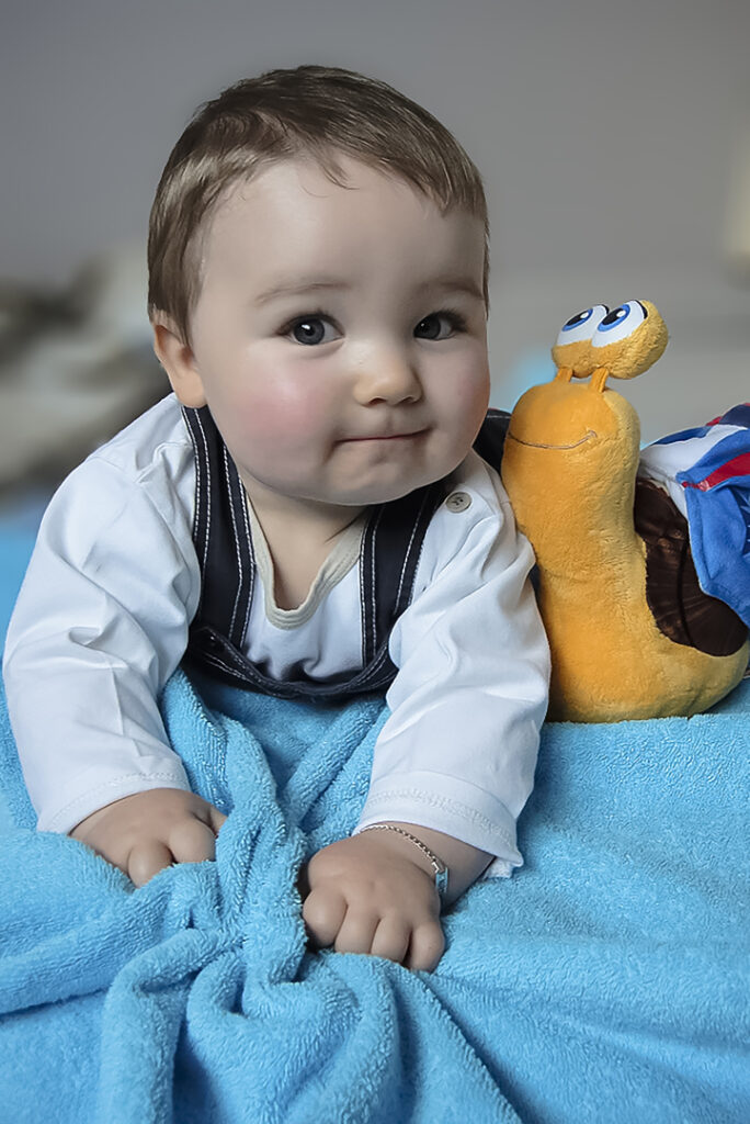 Bébé à 4 pattes sur serviette turquoise avec doudou Photographe famille Bébé Enfant Grossesse Héricourt Haute-Saône Belfort Montbléiard